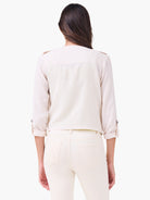 Light cream linen moto jacket, back view. Rolled 3/4 sleeves with button tabs, shoulder epaulets.
