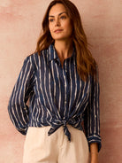 Navy button-down shirt with irregular white watercolor stripes. Tied at the waist, sleeves rolled up.