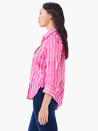 Pink button-up shirt with white watercolor-style vertical stripes. Long sleeves with rolled cuffs, relaxed fit.