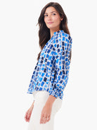 White top with varying blue brushstroke pattern, stand collar, and smocked long sleeves.