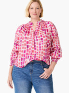 Top with fuchsia and pink brushstroke pattern on white. V-neck, gathered neckline, and 3/4 smocked sleeves.