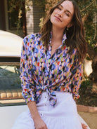 Multicolor button-up shirt with vibrant geometric circle pattern: blue, purple, orange, yellow, black. Worn tied at waist.