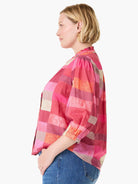 Plaid shirt with ruffled stand collar & 3/4 elastic sleeves in pinks, reds, oranges, & beige blocks.
