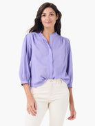 Lavender cotton shirt with ruffled band collar, partial button placket, and 3/4 gathered sleeves.