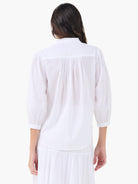White cotton shirt, back view: ruffled stand collar, pleated upper back, 3/4 voluminous sleeves with elasticated cuffs.
