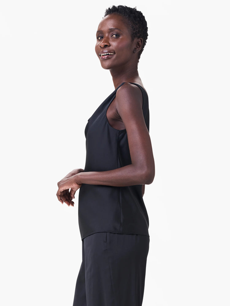 Black sleeveless tank with an asymmetric draped neckline, modeled by a woman.
