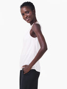 Off-white sleeveless tank top with a drapey fit, shown on a model wearing dark pants.