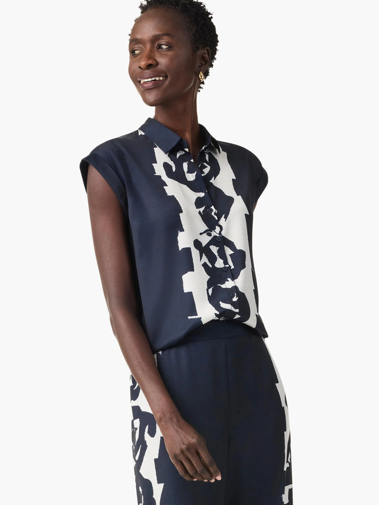 Navy blue collared top with short cuffed sleeves and a bold white abstract pattern.