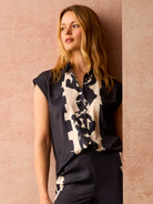 Dark collared top with short cuffed sleeves and a contrasting cream abstract pattern.