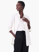 Cream collared shirt, open with cuffed long sleeves, layered over a matching camisole.