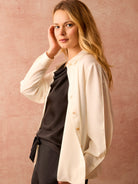 Cream long-sleeve crepe shirt with a collar, button-front, and light buttons. Styled open.