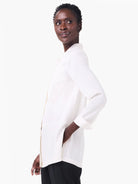 Softly draped off-white collared shirt with cuffed long sleeves and a side pocket.