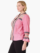 Pink V-neck top with diagonal stripes. Features navy spotted and beige striped trim on front placket and shirred 3/4 cuffs.