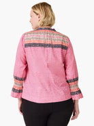 Pink top with diagonal texture. Upper back & smocked cuffs have horizontal stripes: beige, peach, navy, pink, with dots.