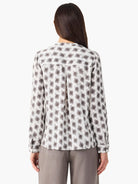 Off-white long-sleeve shirt, back view, with repeating dark grey clover stamp pattern and a pleated yoke.
