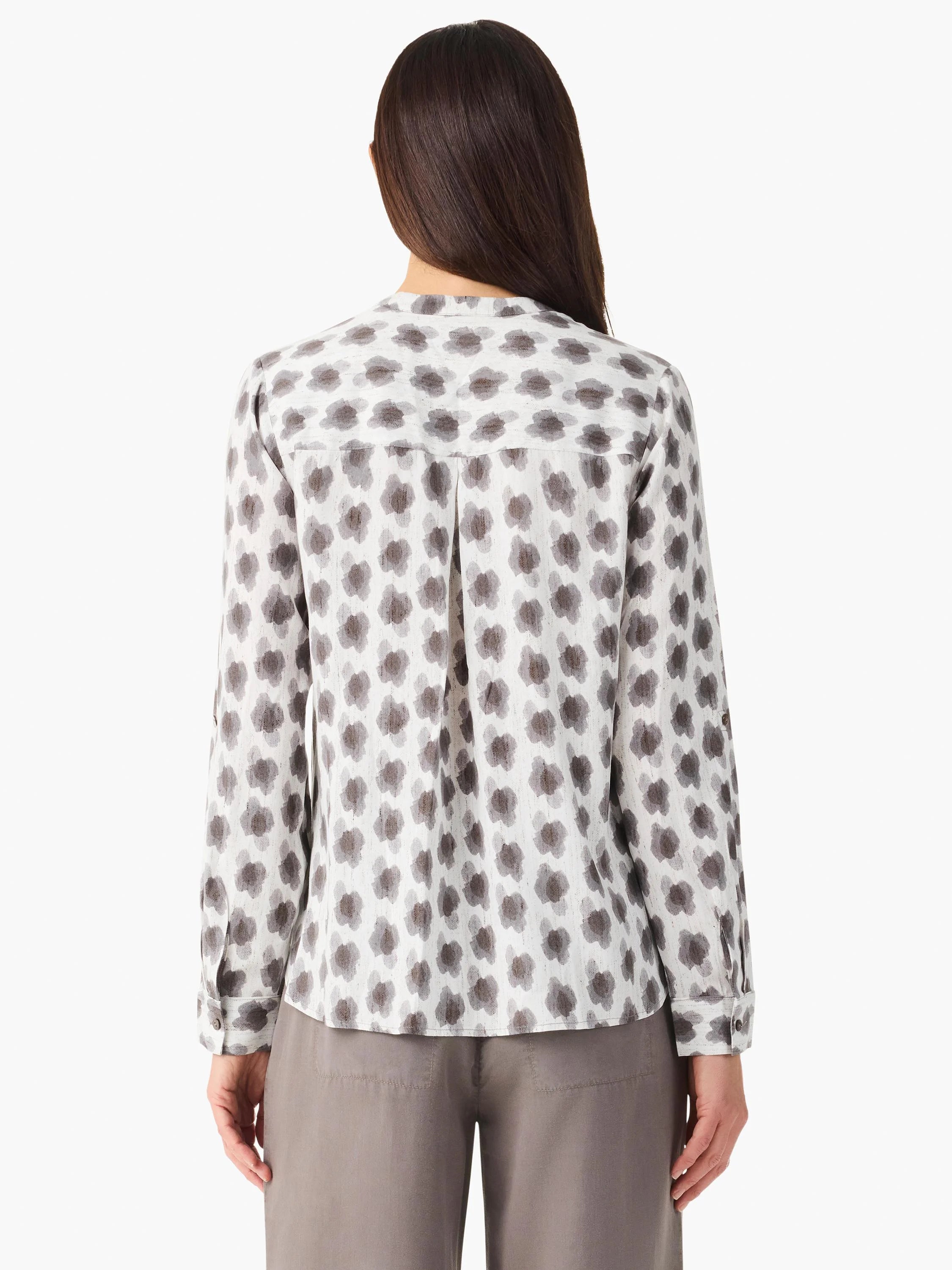 Off-white long-sleeve shirt, back view, with repeating dark grey clover stamp pattern and a pleated yoke.
