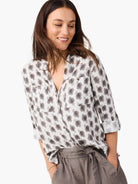 Off-white button-up shirt with gray clover stamp pattern, chest pockets, and rolled sleeves.