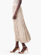 Light beige midi skirt with irregular vertical pleats and a crinkled texture.