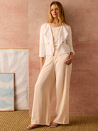Beige wide-leg linen trousers shown on a model.  The trousers are a light, creamy beige.
