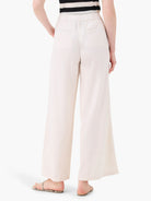 Off-white wide-leg linen trousers with an elasticized waistband and pockets.  Back view.
