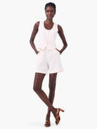 Off-white linen shorts and matching sleeveless top on a model.  Brown heels are also visible.