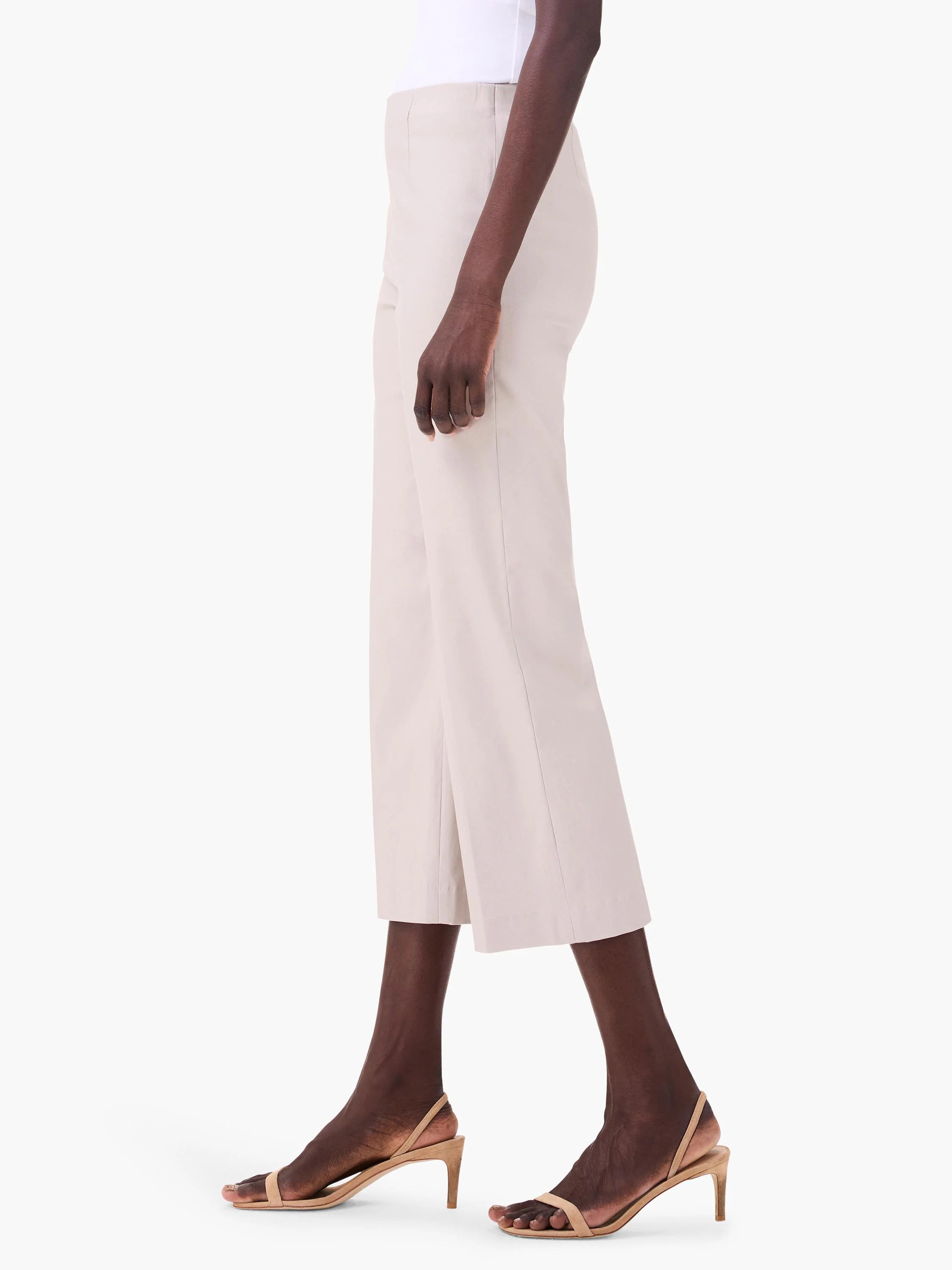 Pale beige wide-leg crop pants, shown on a model from the side, featuring a smooth, polished fabric.