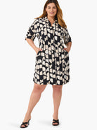 Black shirt dress with beige abstract print, short sleeves, collared neckline, and pockets.