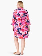 Pink shirt dress with red, orange, and navy leaf print.  Three-quarter sleeves, belted waist.