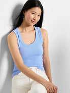 A woman wears a light blue ribbed scoop neck tank.