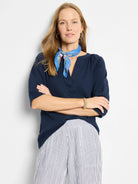 Navy blue, textured knit top with a V-neck and short sleeves. Model also wears a blue patterned scarf.
