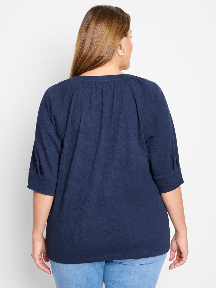 Dark navy blue, textured knit top.  Three-quarter sleeves, round neckline.  Shown from the back.