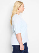 Light blue, crinkled knit top with short, puffed sleeves.  Side profile view.