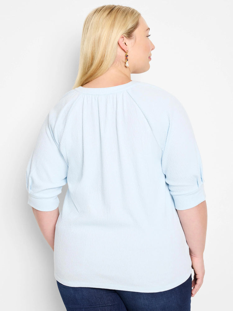 Light blue, textured knit top.  Three-quarter sleeves, round neckline. Back view.