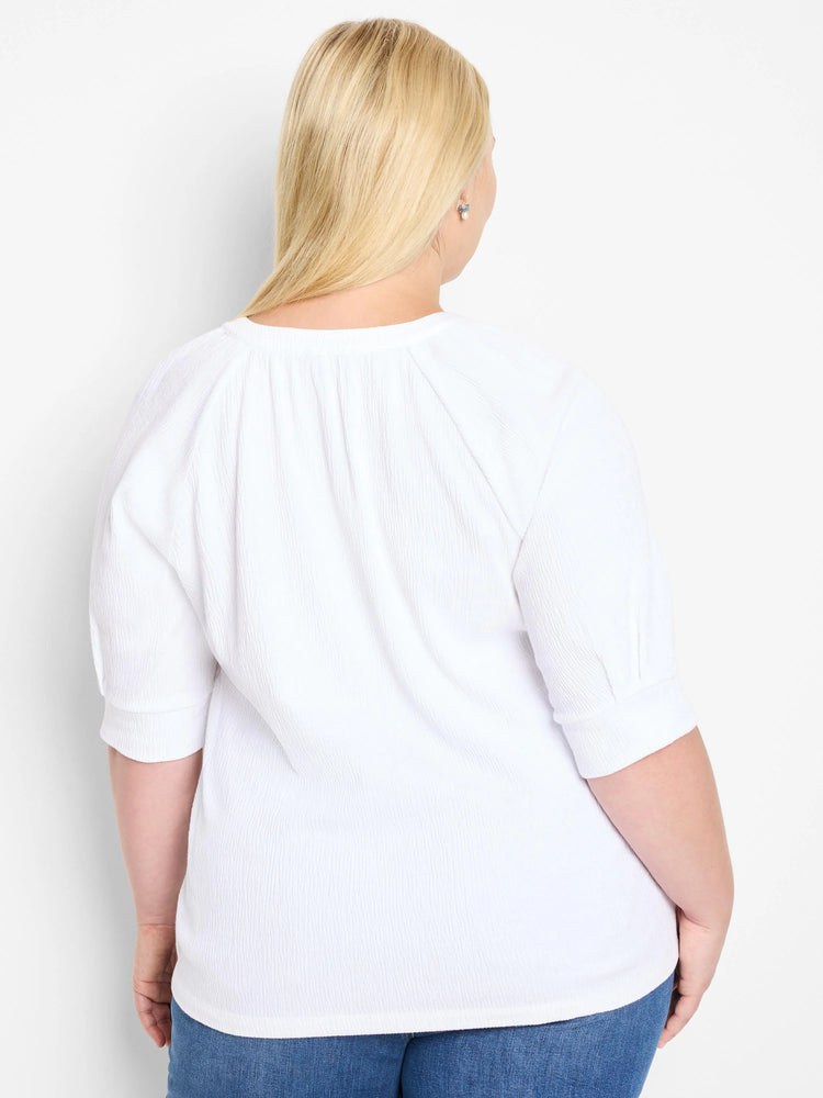 White, textured knit top with short, puffed sleeves and a round neckline.  Shown from the back.