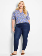 Blue, beige, and black patterned short-sleeve top; dark wash jeans; brown woven sandals.