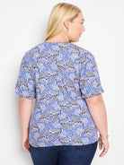 Blue short-sleeve top with a repeating geometric pattern in beige and black.