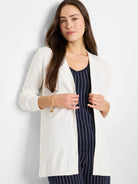 Off-white cardigan, long sleeves, button front.  Model wears it over a navy pinstripe top.