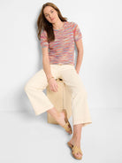 Short-sleeved, multicolored knit sweater tee with horizontal stripes in pink, orange, blue, and white.