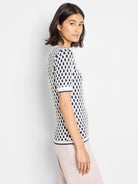 Off-white short-sleeve sweater tee with navy blue and gold stitch detailing.  Pattern is small, repeating oval shapes.