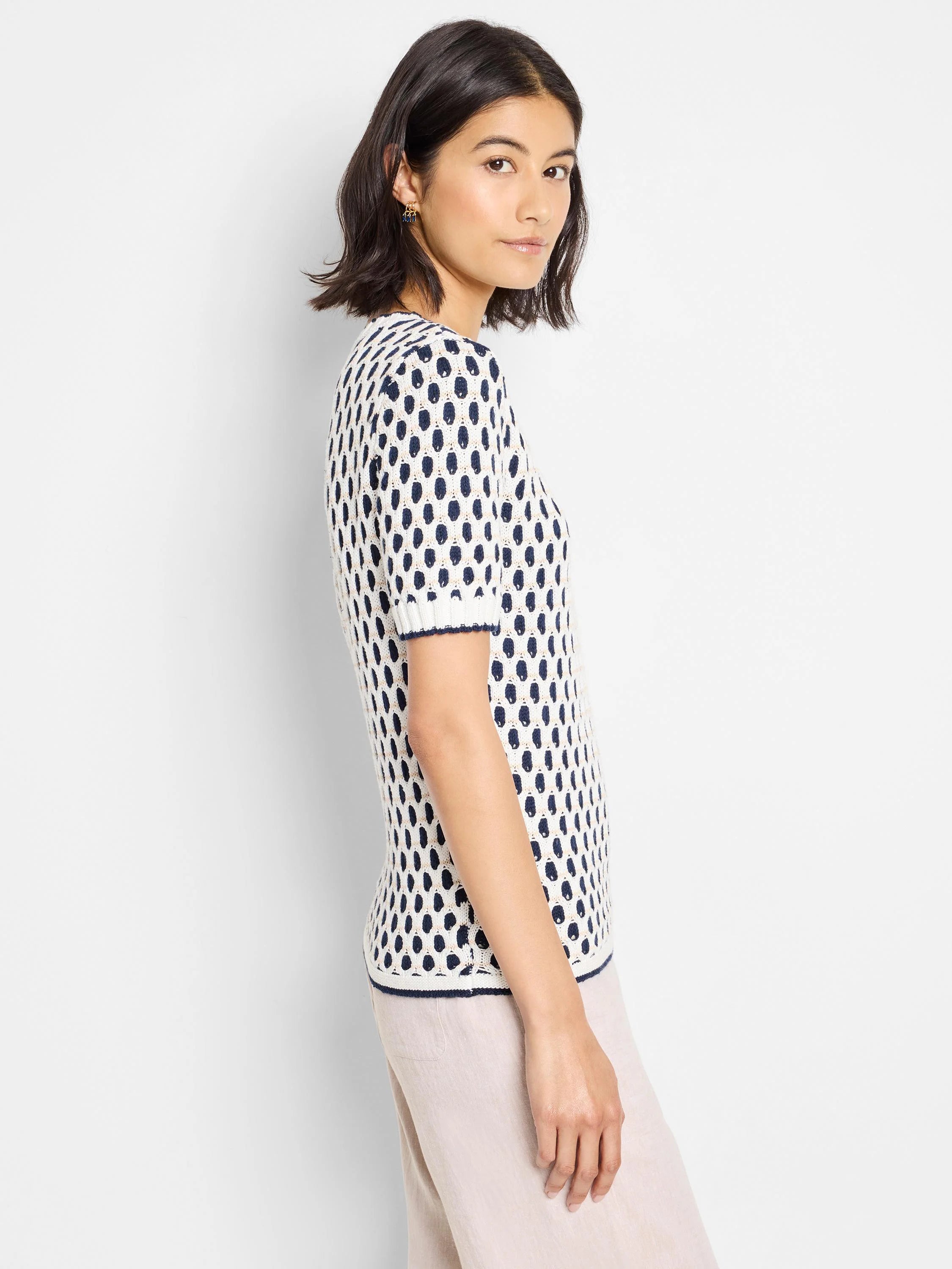 Off-white short-sleeve sweater tee with navy blue and gold stitch detailing.  Pattern is small, repeating oval shapes.