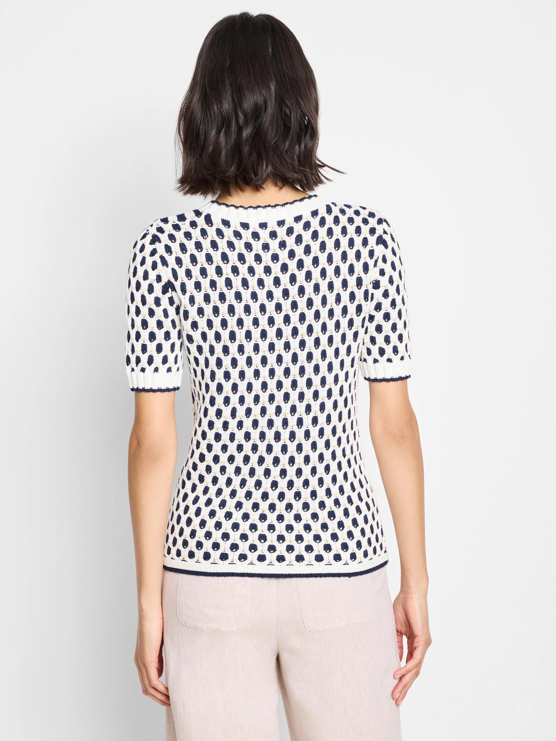 Cream-colored short-sleeve sweater with navy blue geometric pattern.  Back view.