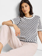 Cream short-sleeve sweater with navy blue and beige honeycomb pattern.  Knit fabric.