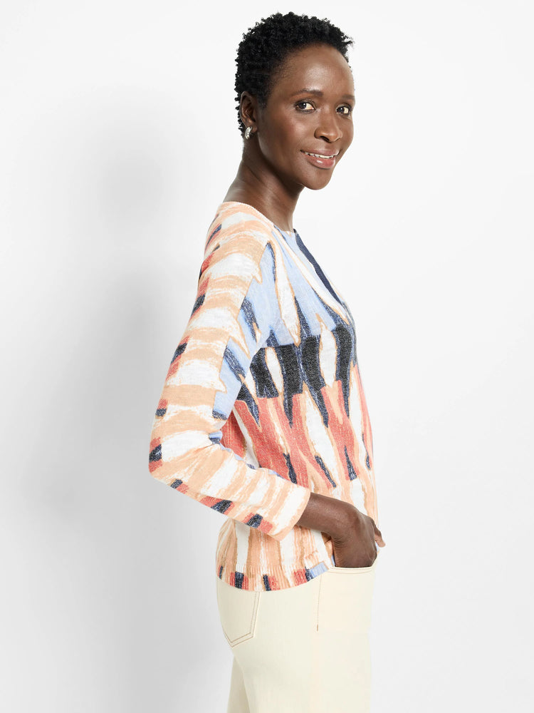 Long-sleeved sweater with abstract print in peach, light blue, and dark gray on a white background.  Criss-cross detail...