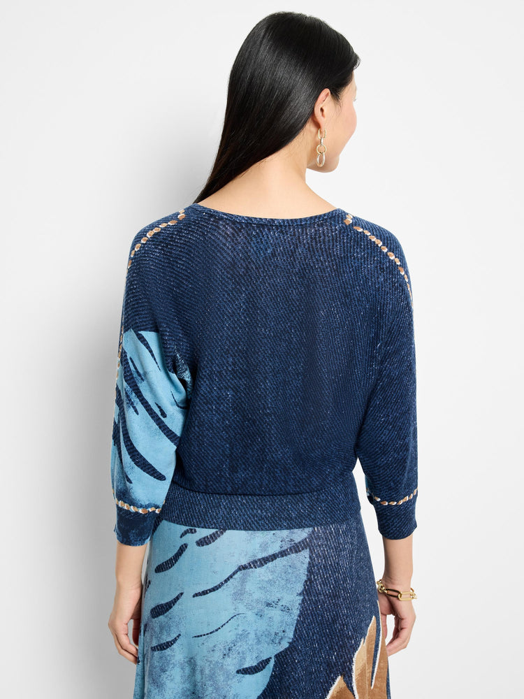 Here's alt text under 125 characters:

"Back view of navy blue V-neck sweater with light blue abstract print and tan...