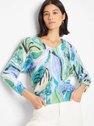 Cotton sweater with abstract leaf print in teal, light blue, green, and cream on a white background. Three-quarter...