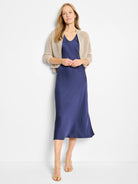 Light beige mesh cocoon cardigan with an open knit, short length, worn over a blue dress.