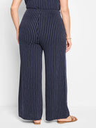 Navy blue wide-leg pants with thin white vertical stripes.  Back view.