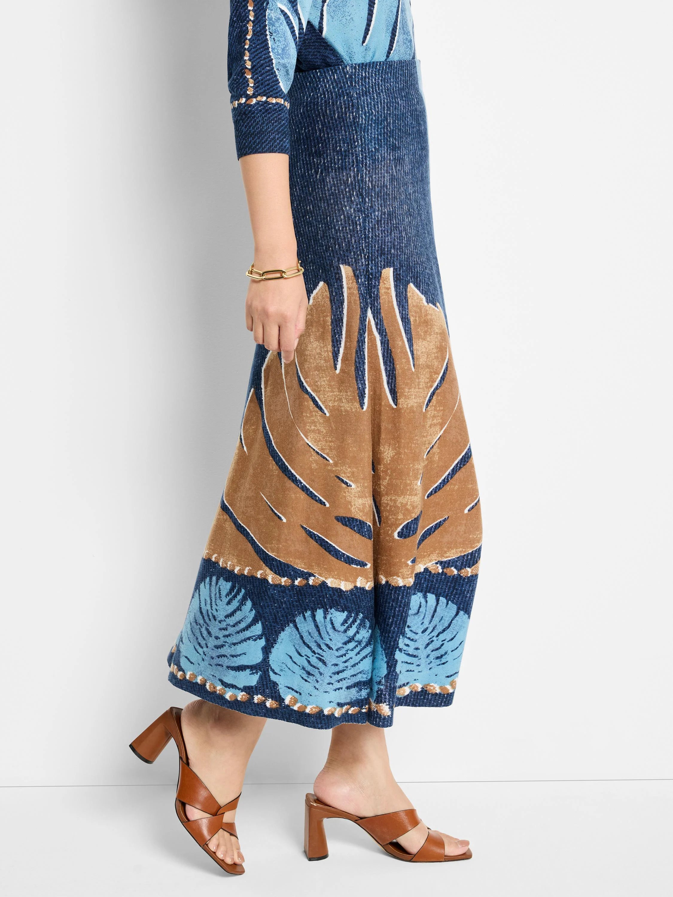 Blue knit midi skirt with brown leaf print and lighter blue accents.  Features a textured knit fabric.