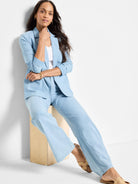 Light blue linen-denim blazer and pants.  Relaxed fit. Model seated.