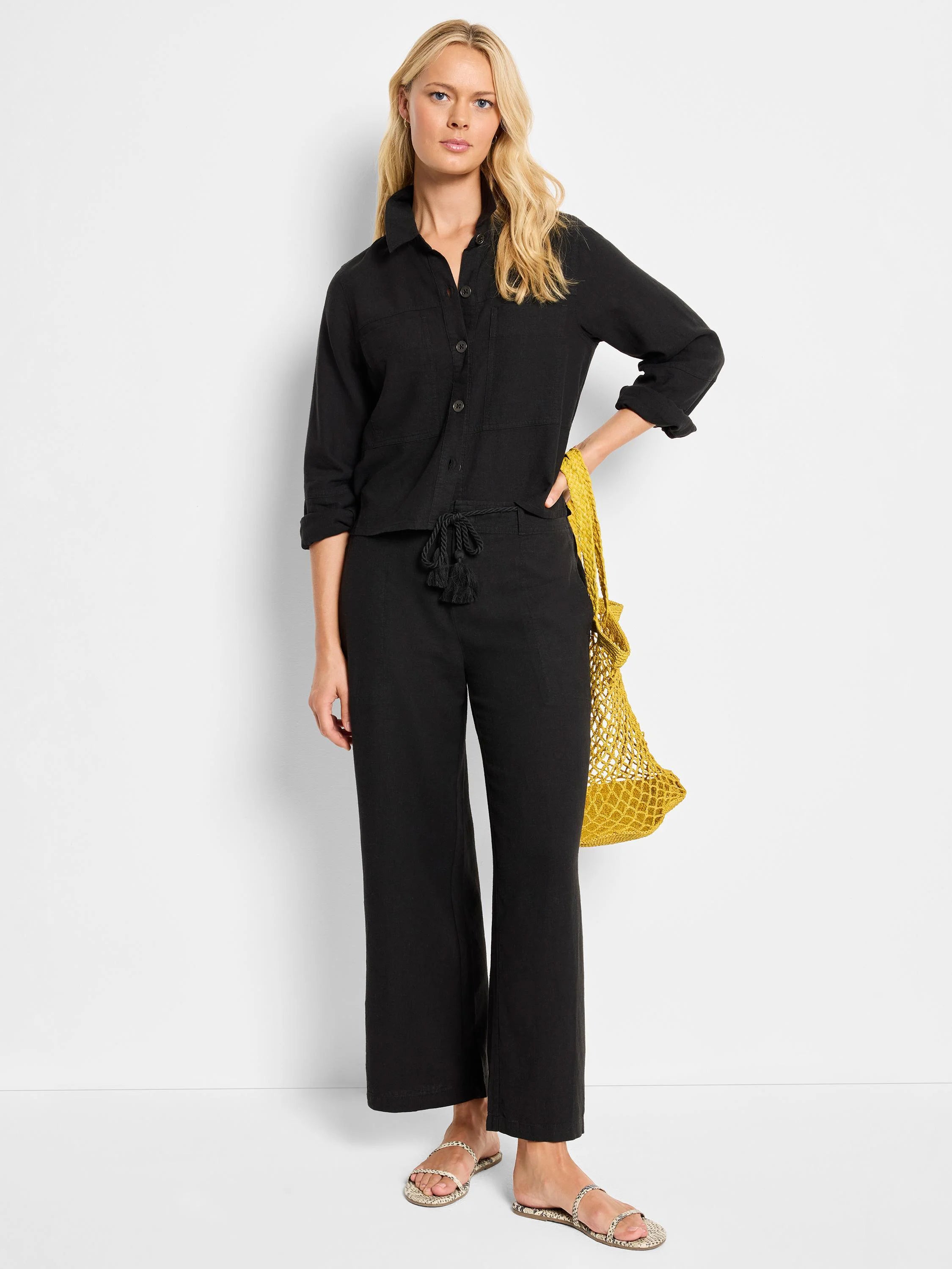 Black linen jacket with button front and pockets, worn with black pants and a drawstring waist.
